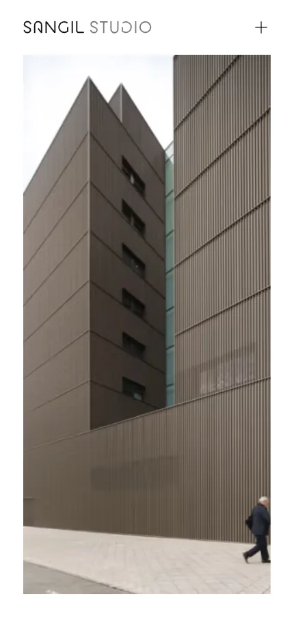 Primera pantalla de la web de Sangil Studio: una fotografía de arquitectura a pantalla completa sin ningún texto encima, con el logotipo del estudio arriba a la izquierda y un signo más para abrir el menú arriba a la derecha, sobre fondo blanco.
